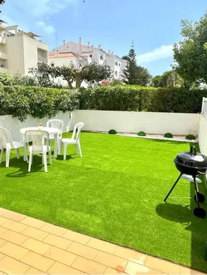 a lawn with white chairs and a table and a fence at Amazing Studio Flat Albufeira in Albufeira