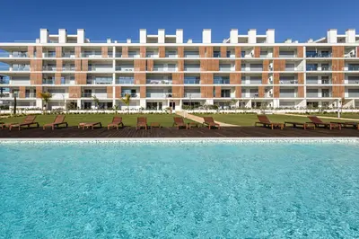 a large building with benches in front of a swimming pool at The Albufeira Concierge - Prime Sunset Design in Albufeira