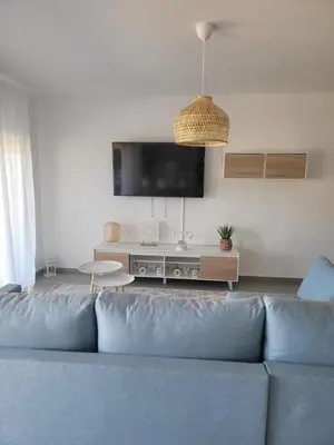 a living room with a blue couch and a flat screen tv at The Albufeira Concierge - Prime Sunset Design in Albufeira
