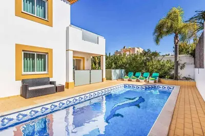 a swimming pool in front of a house at Villa Astro in Albufeira