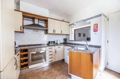 a kitchen with white cabinets and a sink at Villa Ninos in Albufeira