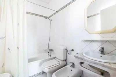 a white bathroom with a toilet and a sink at Villa Ninos in Albufeira
