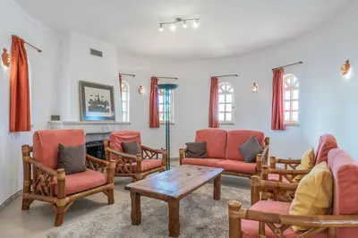 a living room with chairs and a table and a fireplace at Villa Noras in Albufeira