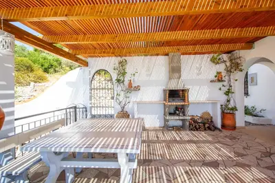 a porch with a table and a fireplace at Villa Jacaranda Bordeira in Corotelo