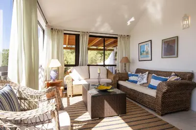 a living room with a couch and chairs at Villa Jacaranda Bordeira in Corotelo