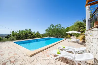 a swimming pool with two lounge chairs next to a house at Villa Jacaranda Bordeira in Corotelo