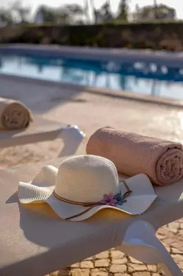 a straw hat and a rolled up towel on a beach at Al Meida Guesthouse in Albufeira