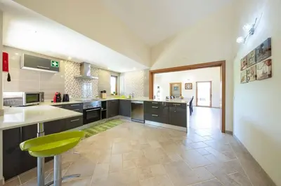 a large kitchen with black cabinets and a green stool at Casa Salir in Salir