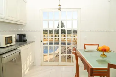 a white kitchen with a table and a window at Seaside Serenity Villa in Albufeira