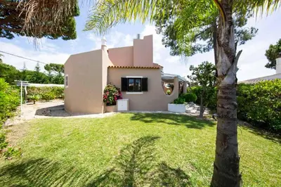 a house with a palm tree in front of a yard at Villa Silveira II in Vilamoura
