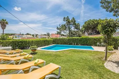 a swimming pool in a yard with lounge chairs at Villa Silveira II in Vilamoura