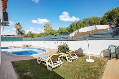 a patio with two chairs and an umbrella next to a pool at Villa Luísa Galé in Albufeira
