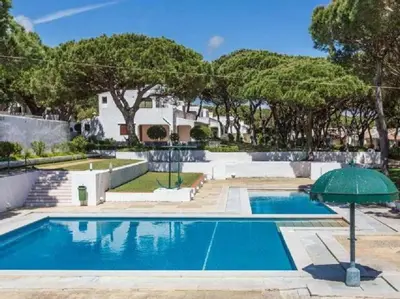 a swimming pool with an umbrella in front of a house at TAC - Açoteias Budget Studio in Olhos de Água