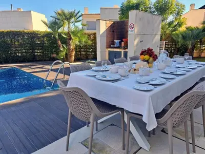 a dining table with a white tablecloth and chairs next to a pool at Villa Corcovada Lote 28 VIP Properties by Interhome in Albufeira
