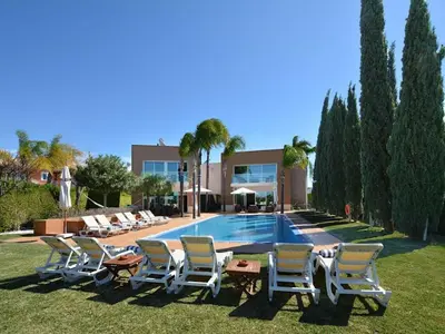 a group of lounge chairs and a swimming pool at Special Vilamoura Villa 6 Bedrooms Villa Lagoon Private Pool in Quarteira