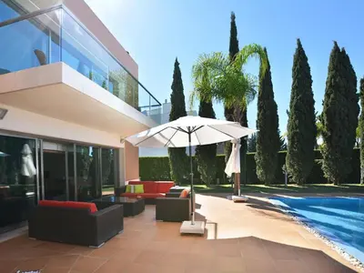 a patio with an umbrella next to a pool at Special Vilamoura Villa 6 Bedrooms Villa Lagoon Private Pool in Quarteira