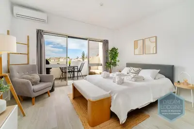 a white bedroom with a bed and a dining room at Moai - Dream Lodging in Albufeira