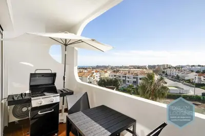 a balcony with a stove and an umbrella at Moai - Dream Lodging in Albufeira