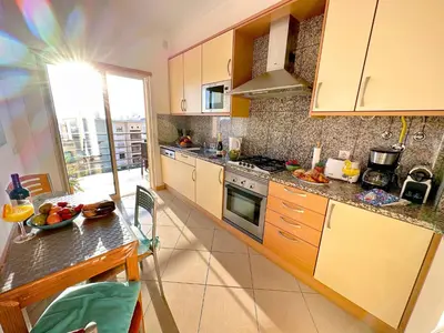 a kitchen with wooden cabinets and a table and a window at AlbufeiraOrada Cozy&Sunny Condo by BeCherish in Albufeira