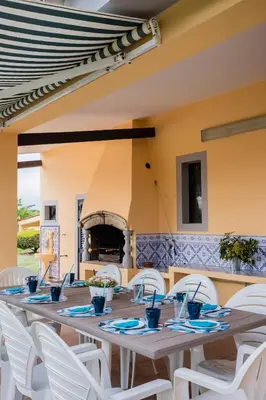 a long table with white chairs and a fireplace at Quinta Vita - Vila Limao in Almancil