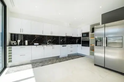 a kitchen with white cabinets and stainless steel appliances at Villa Kambole in Albufeira