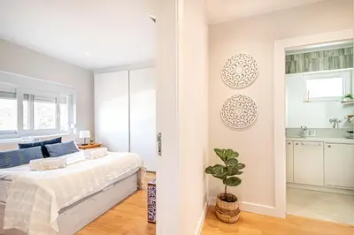 a white bedroom with a bed and a kitchen at BeGuest Falésia Beach & Barbecue Apartment in Albufeira