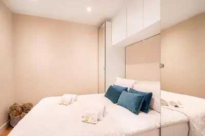 a bedroom with a large white bed with blue pillows at BeGuest Falésia Beach & Barbecue Apartment in Albufeira