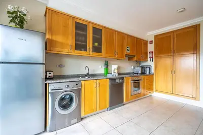 a kitchen with wooden cabinets and a washing machine at Monte Balaia AT19 Duplex - Pool View Olhos de Agua in Olhos de Água