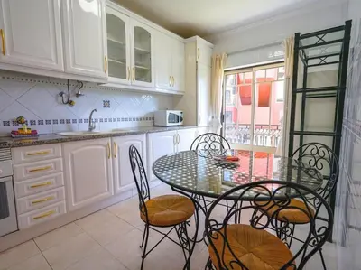 a kitchen with a table and chairs in a kitchen at Oura Sunrise 16 Apartment by Stay ici Algarve Holiday Rental in Albufeira