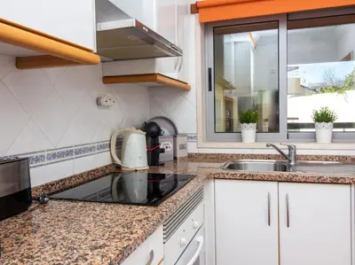 a kitchen with white cabinets and a sink and a window at Globe 33 Apartment by Stay ici Algarve Holiday Rental in Albufeira