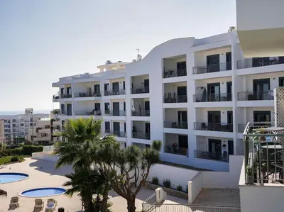 a large white apartment building with a courtyard and palm trees at View Waves Apartment by Stay ici Algarve Holiday Rental in Albufeira