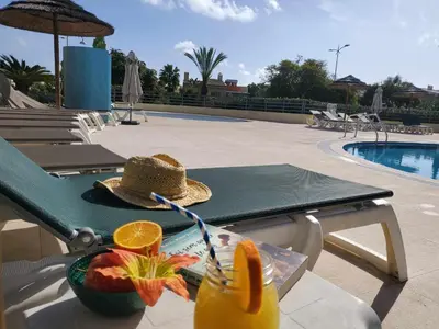 a table with a drink and a bowl of fruit next to a pool at Sun & Nature Apartment Corcovada in Albufeira