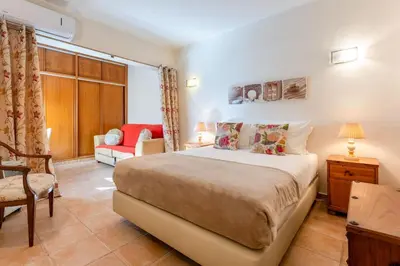a bedroom with a large bed and a chair at Cozy 2 BDR W/Balcony in Vale do Lobo by LovelyStay in Vale do Lobo