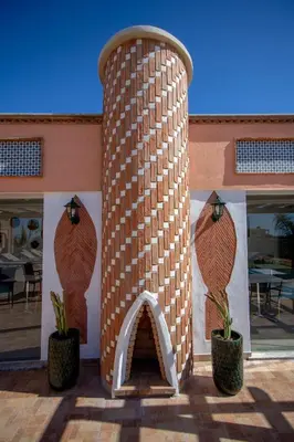 a brick pillar with two potted plants in front of a building at Al Karob Yoga Boutique Hotel in Guia