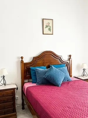 a bedroom with a bed with a red comforter and blue pillows at Casa Brito in Albufeira