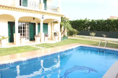 a swimming pool in front of a house at Vila Montechoro in Albufeira