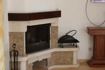 a stone fireplace with a black bell on it at Vila Montechoro in Albufeira