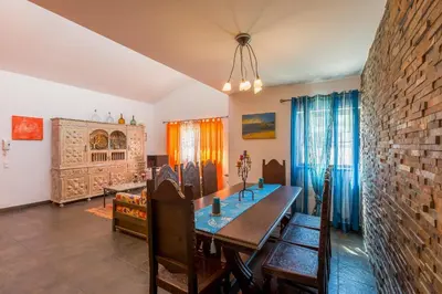 a dining room with a table and a brick wall at VILA RUINAS GAMITO in Guia