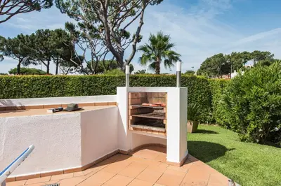 a barbecue in a garden next to a hedge at Mng Elliott52 in Vale do Lobo