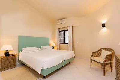 a bedroom with a bed and a chair and a window at Mng Elliott25 in Vale do Lobo