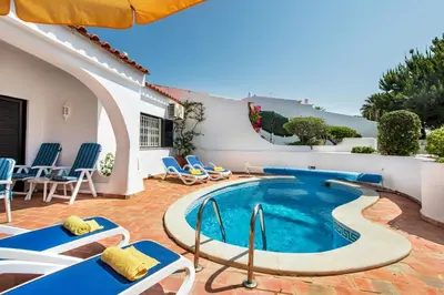a swimming pool with chairs and an umbrella at Mng Elliott13 in Vale do Lobo