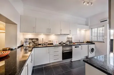 a kitchen with white cabinets and a washer and dryer at Mng Elliott72 in Vale do Lobo