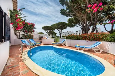 a swimming pool with chairs and flowers on a patio at Mng Elliott71 in Vale do Lobo
