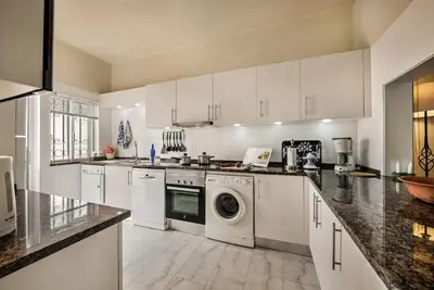 a kitchen with white cabinets and a washer and dryer at Mng Elliott49 in Almancil