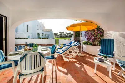 a dining room with a white table and blue chairs at Mng Elliott42 in Vale do Lobo