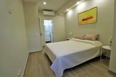 a bedroom with a white bed and a painting on the wall at Apartamento laranja Quarteira in Quarteira