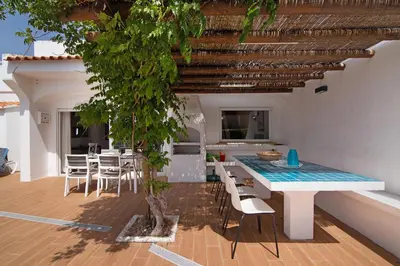 a large blue swimming pool with a fence and palm trees at Villa Aveiros in Albufeira