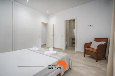a white bedroom with a bed and a chair at #213 Vila Roja Pé by Home Holidays in Albufeira