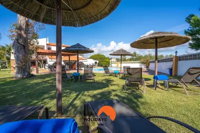 a group of chairs and umbrellas next to a pool at #213 Vila Roja Pé by Home Holidays in Albufeira