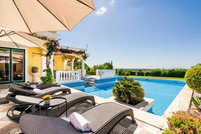 a villa with a swimming pool with chairs and an umbrella at TheBougainVilla our Oceanview Villa in the Hills in Boliqueime